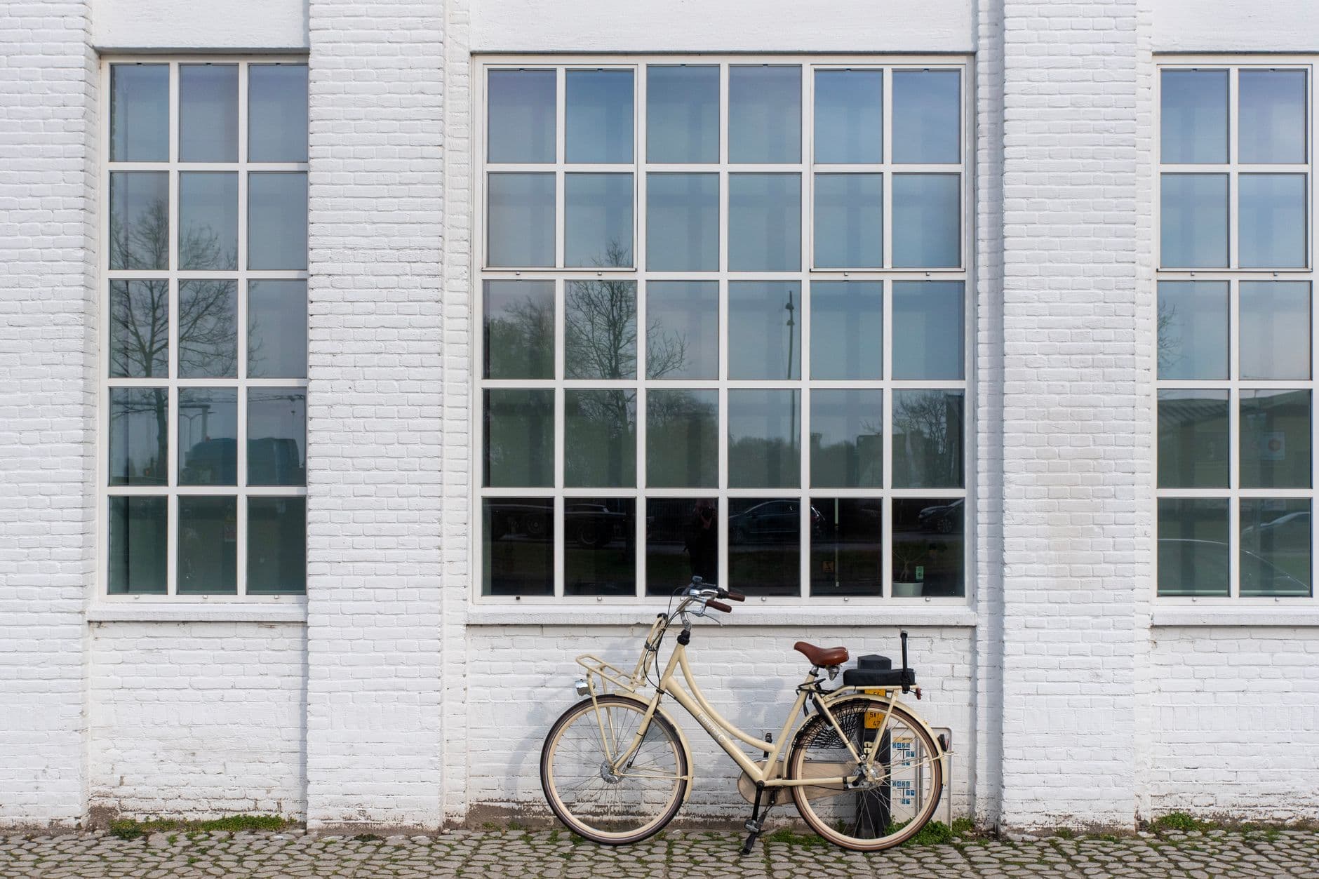Vintage bicycle against a white brick wall with tall windows